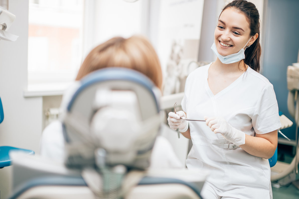 friendly dentist woman treating beautiful patient in dental office, doctor in white uniform, professional orthodontist